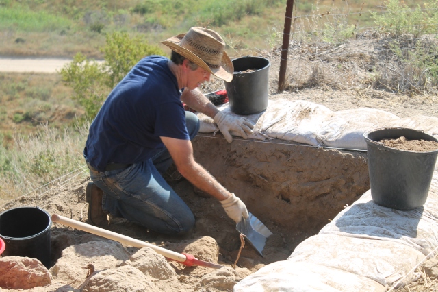 Dr. David McClister collecting sediment and cleaning the baulk in his square. The baulk is the edge of a square that shows the strata (layers) as you excavate down to different levels. (Photo by Luke Chandler)